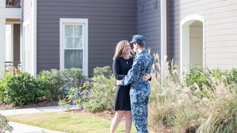 military couple in front of home, military homebuying tips