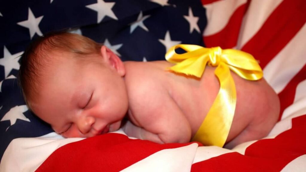 military baby, on an American flag, wrapped in a yellow ribbon